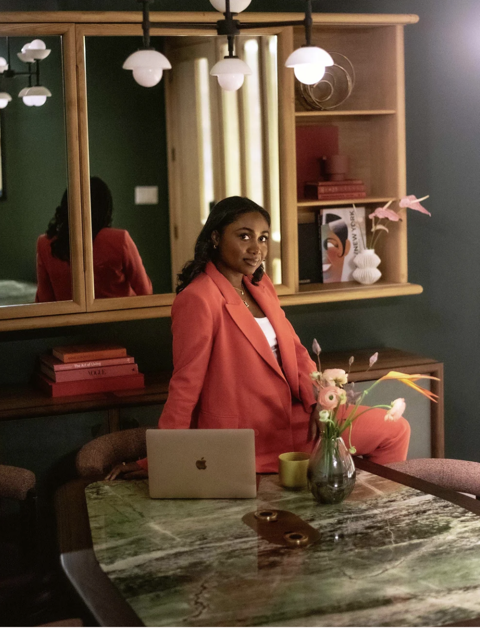 Lydia, founder of Boardroom Beauty, in a coral suit at her laptop